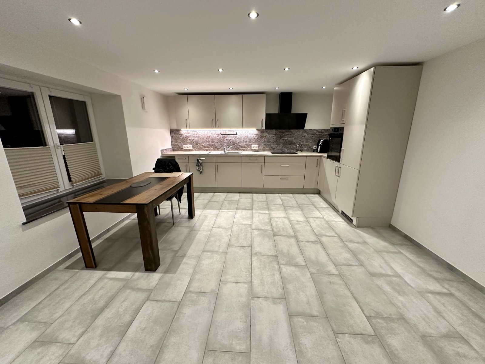 Moderne L-Küche mit Natursteinrückwand 