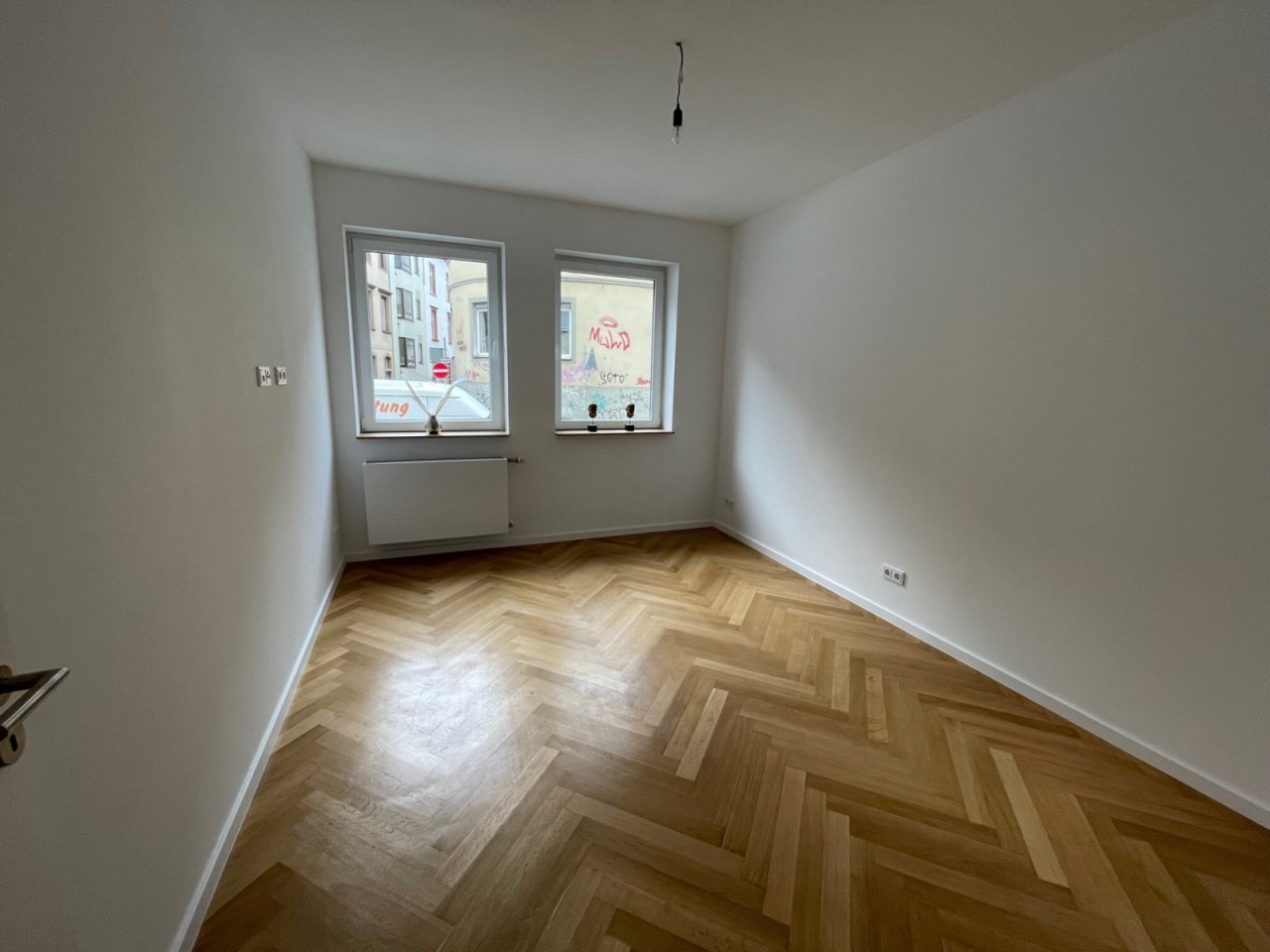 Stilvoller Wohnraum mit elegantem Fischgrät-Parkett und lichtdurchfluteten Fenstern Stilvoller Wohnraum mit elegantem Fischgrät-Parkett und lichtdurchfluteten Fenstern