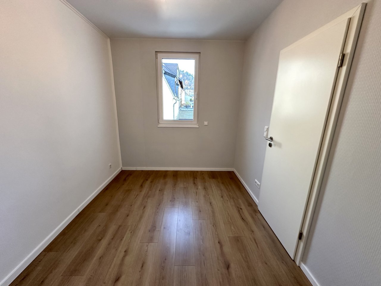 Lichtdurchflutetes Zimmer mit hochwertigen Laminat Ausstattung und elegantem Fensterblick Lichtdurchflutetes Zimmer mit hochwertigen Laminat Ausstattung und elegantem Fensterblick