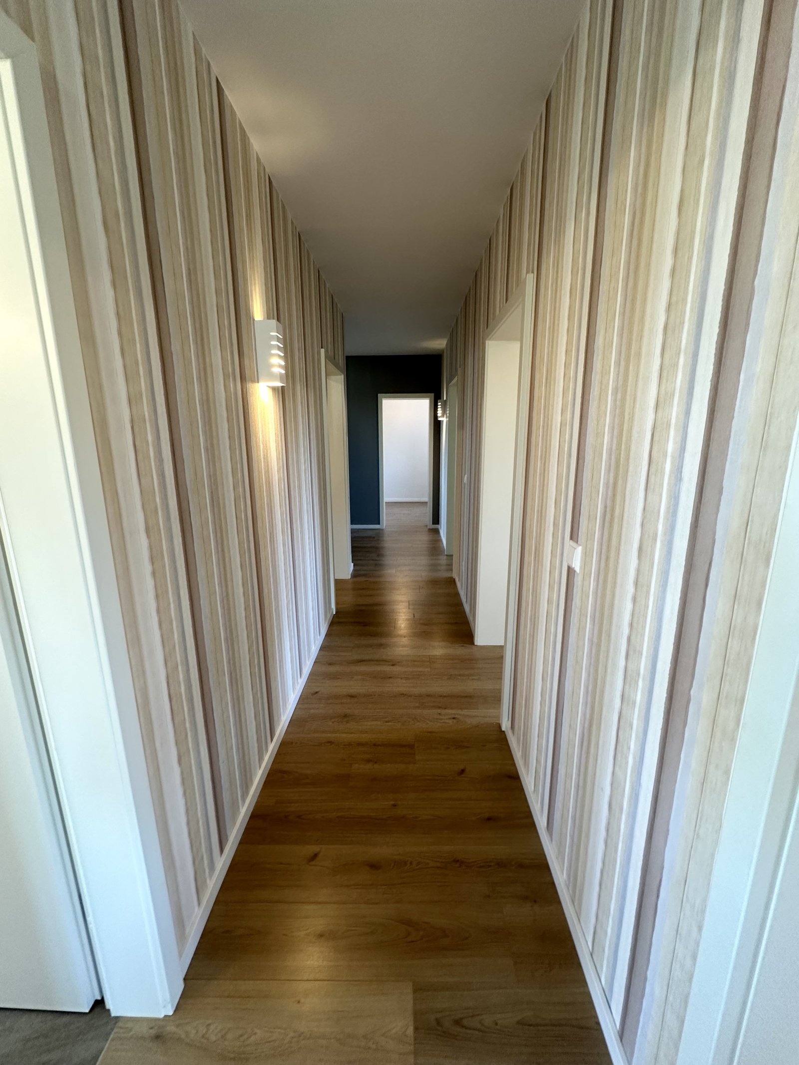 Lichtdurchfluteter Designflur mit eleganter Holzboden-Optik und strukturierter Wandgestaltung Lichtdurchfluteter Designflur mit eleganter Holzboden-Optik und strukturierter Wandgestaltung