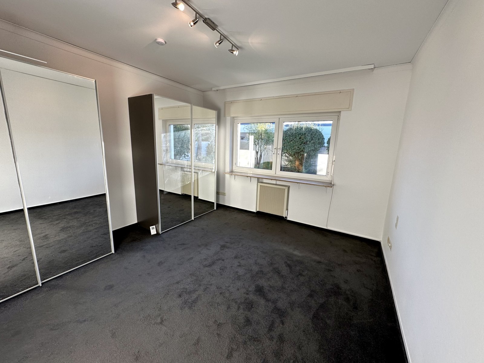 Lichtdurchflutetes Zimmer mit Spiegelschrank und Gartenblick