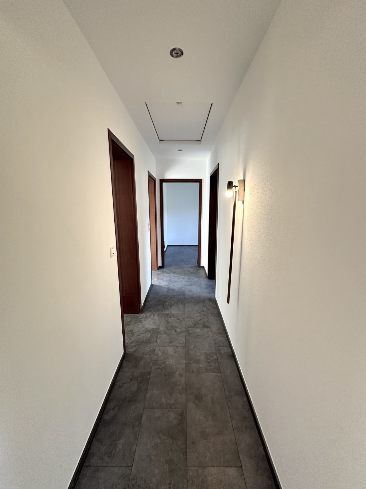 Lichtdurchfluteter Flur mit hochwertiger Beleuchtung und eleganten Türelementen