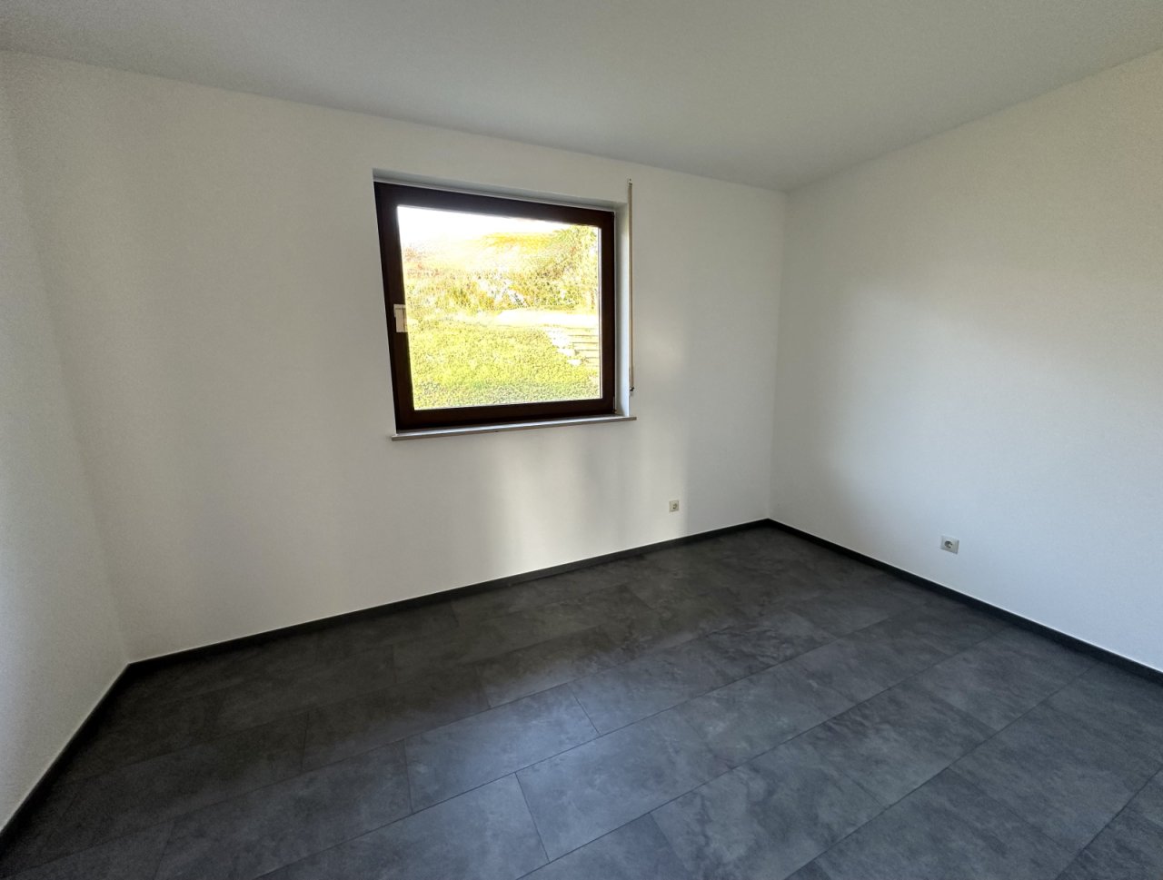 Lichtdurchflutetes Zimmer mit hochwertiger Bodenbeschichtung und Gartenblick