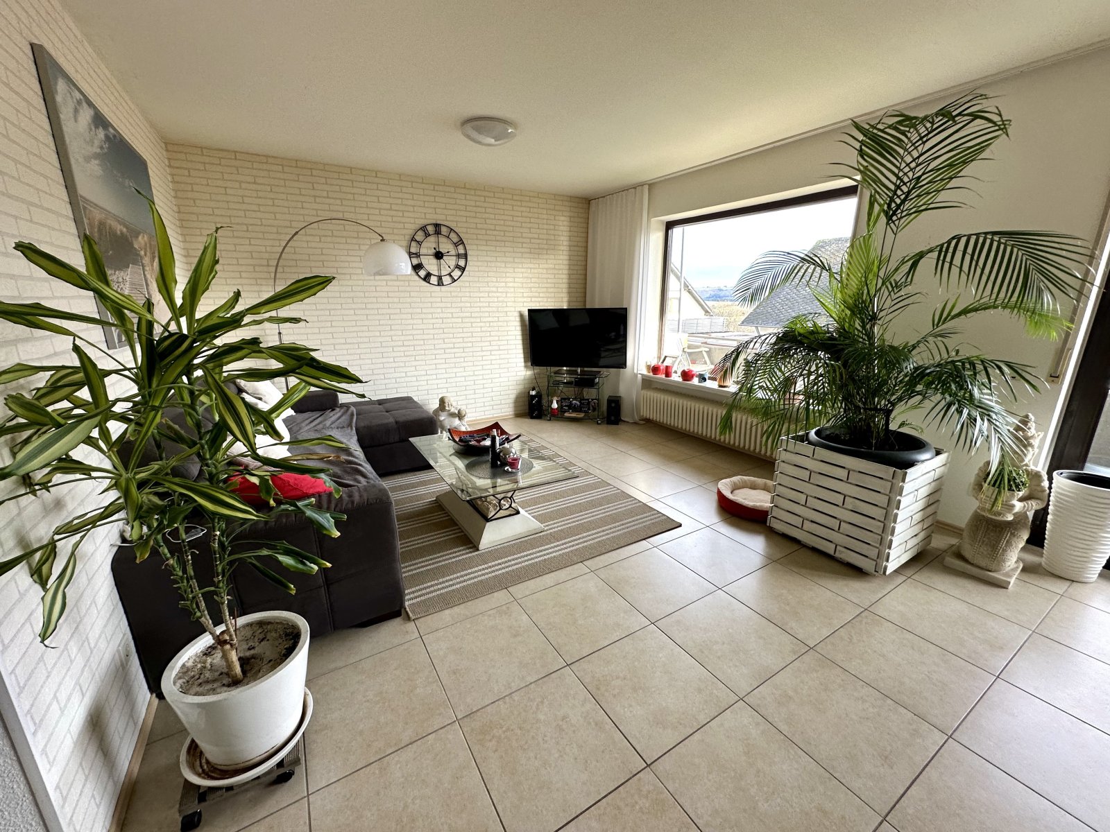 Lichtdurchflutetes Wohnzimmer mit Panoramafenster und eleganter Naturstein-Optik