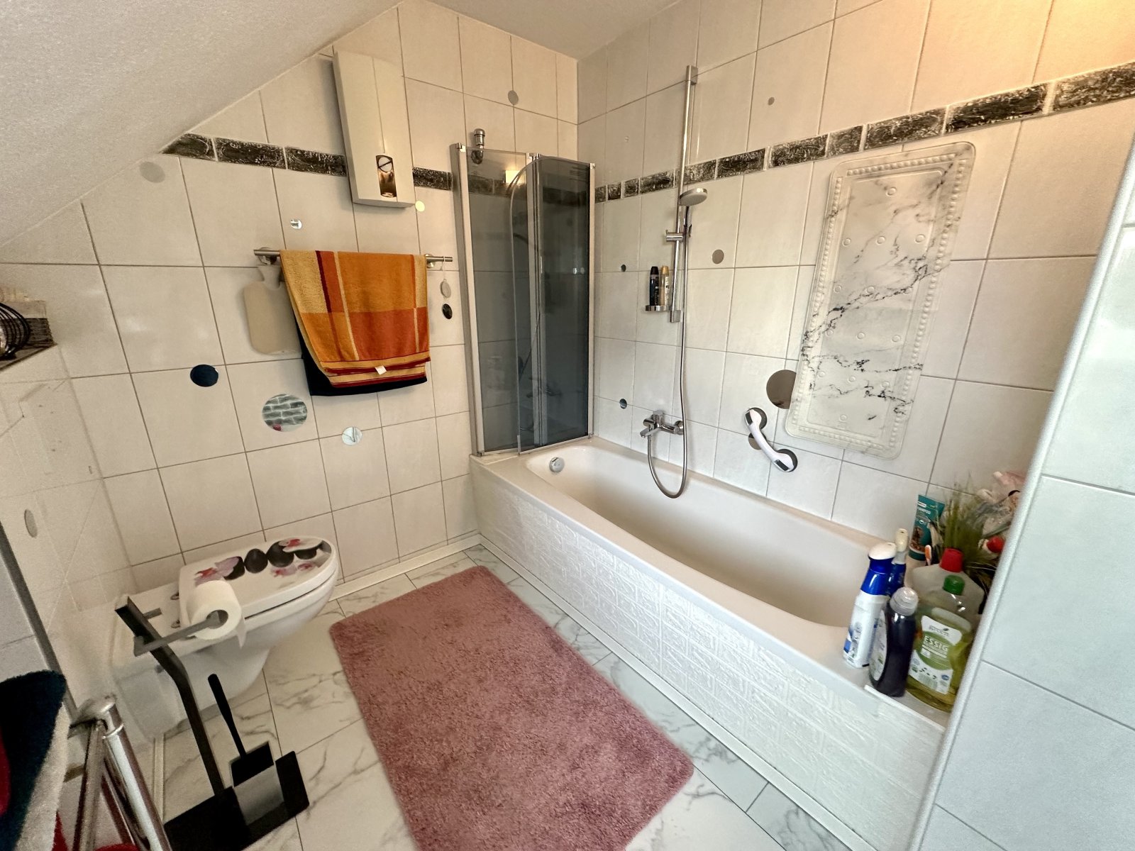 Komfortables Wannenbad mit Duschkabine und praktischer Ausstattung