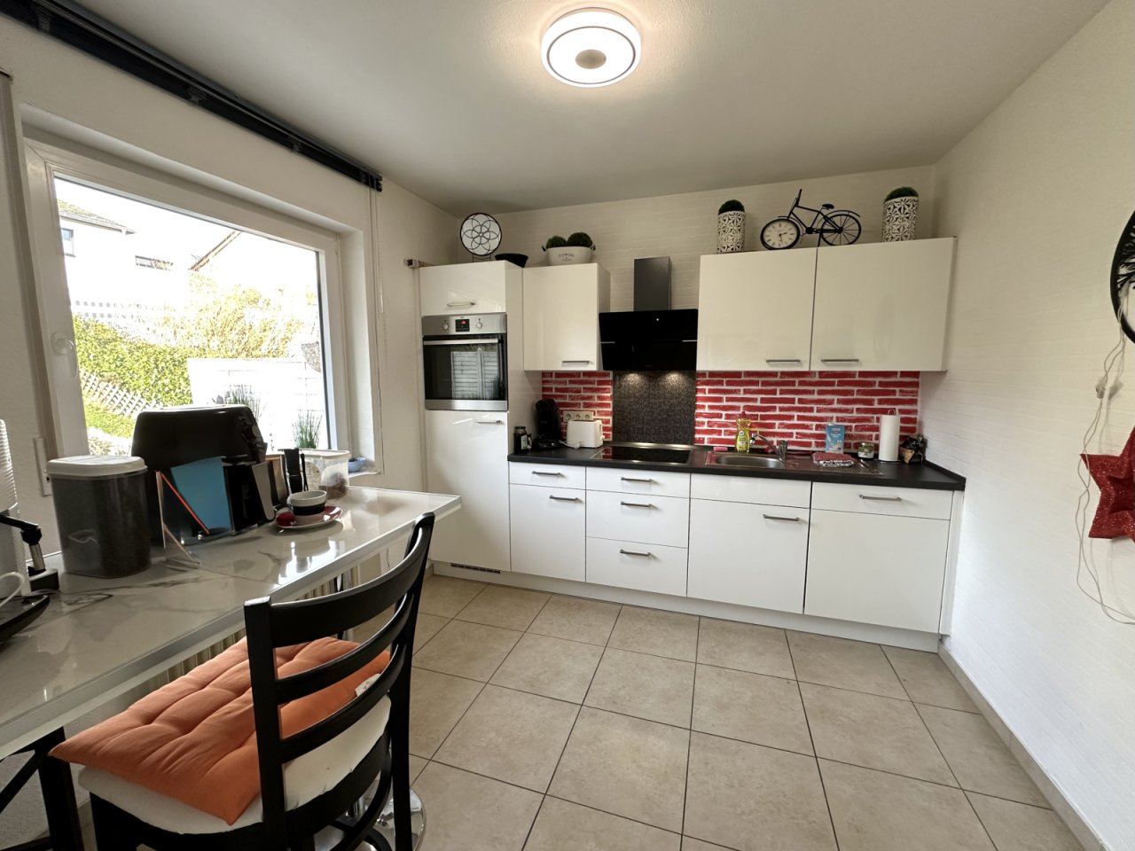 Moderne Einbauküche mit rotem Ziegelrückwand und Tageslichteinfall - Kochen mit Panoramablick!