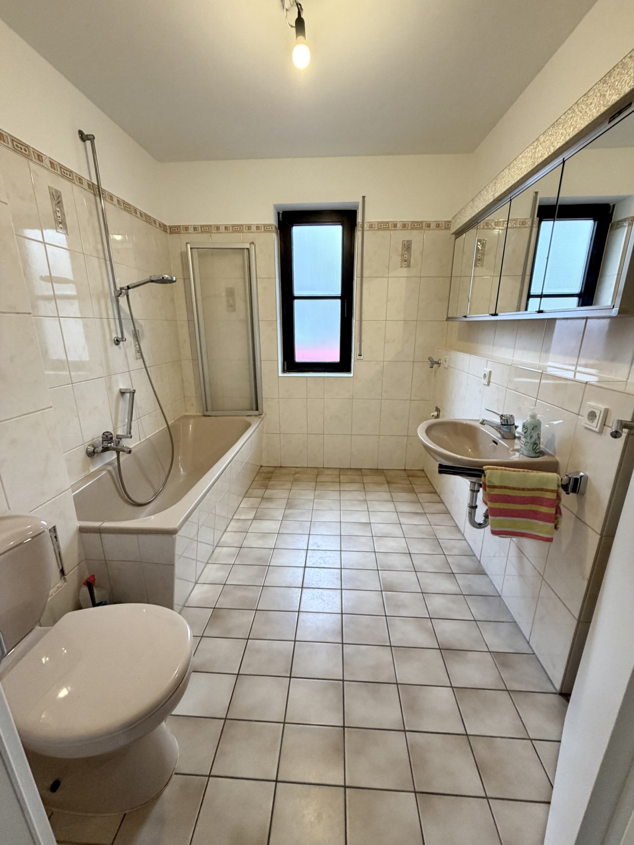 Helles Badezimmer mit Wanne und Duschabtrennung