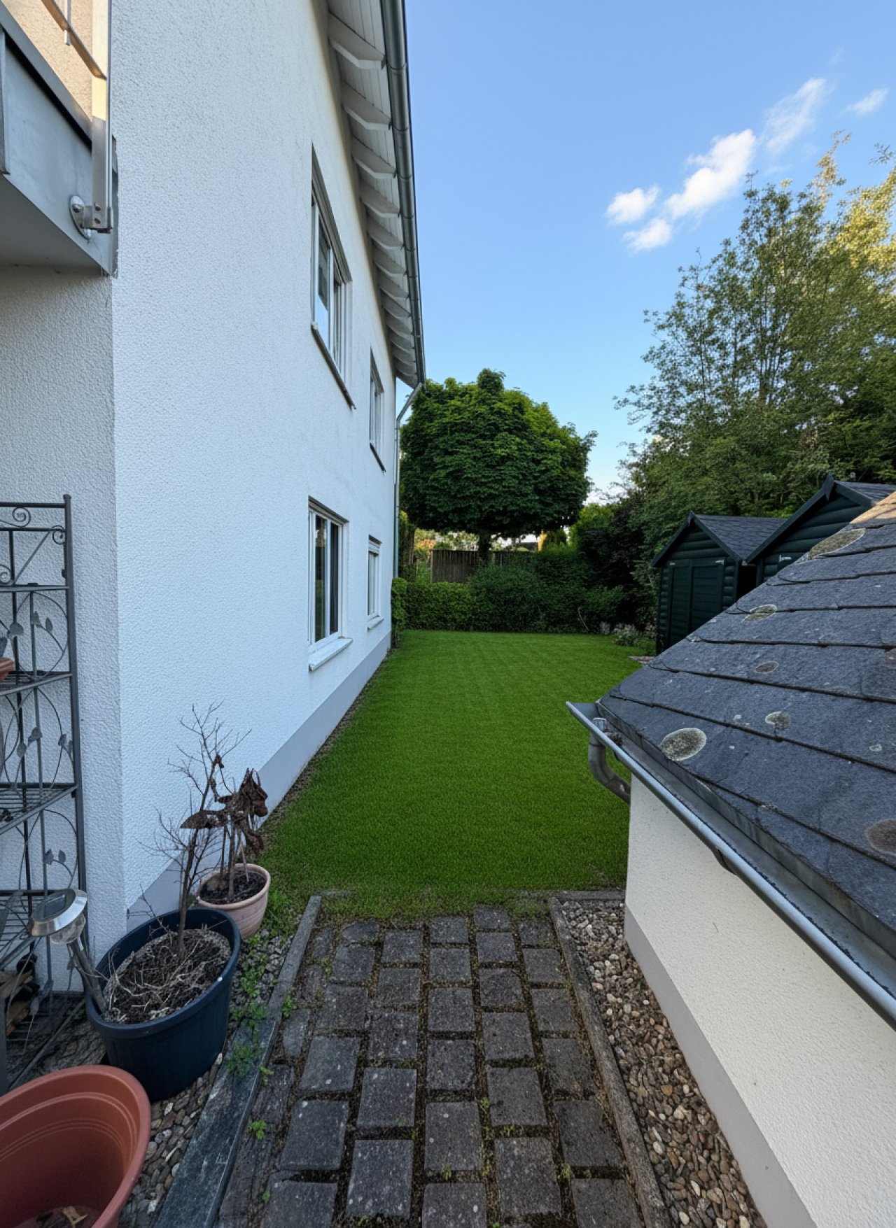 Gepflegter Seitengarten mit Rasenfläche und Nebengebäude Gepflegter Seitengarten mit Rasenfläche und Nebengebäude