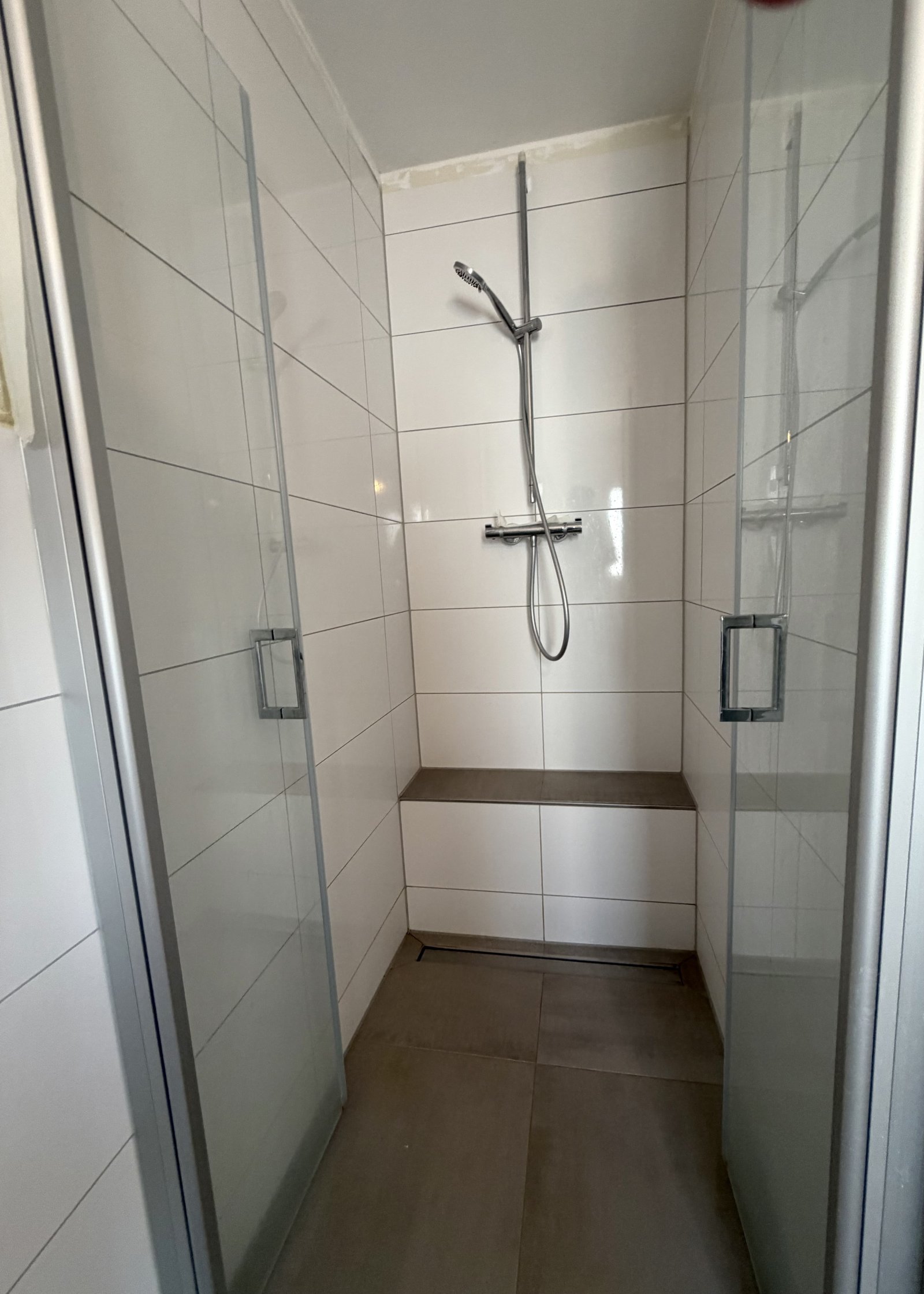 Ebenerdige Dusche mit komfortabler Sitznische und modernem Glastrennwand-System