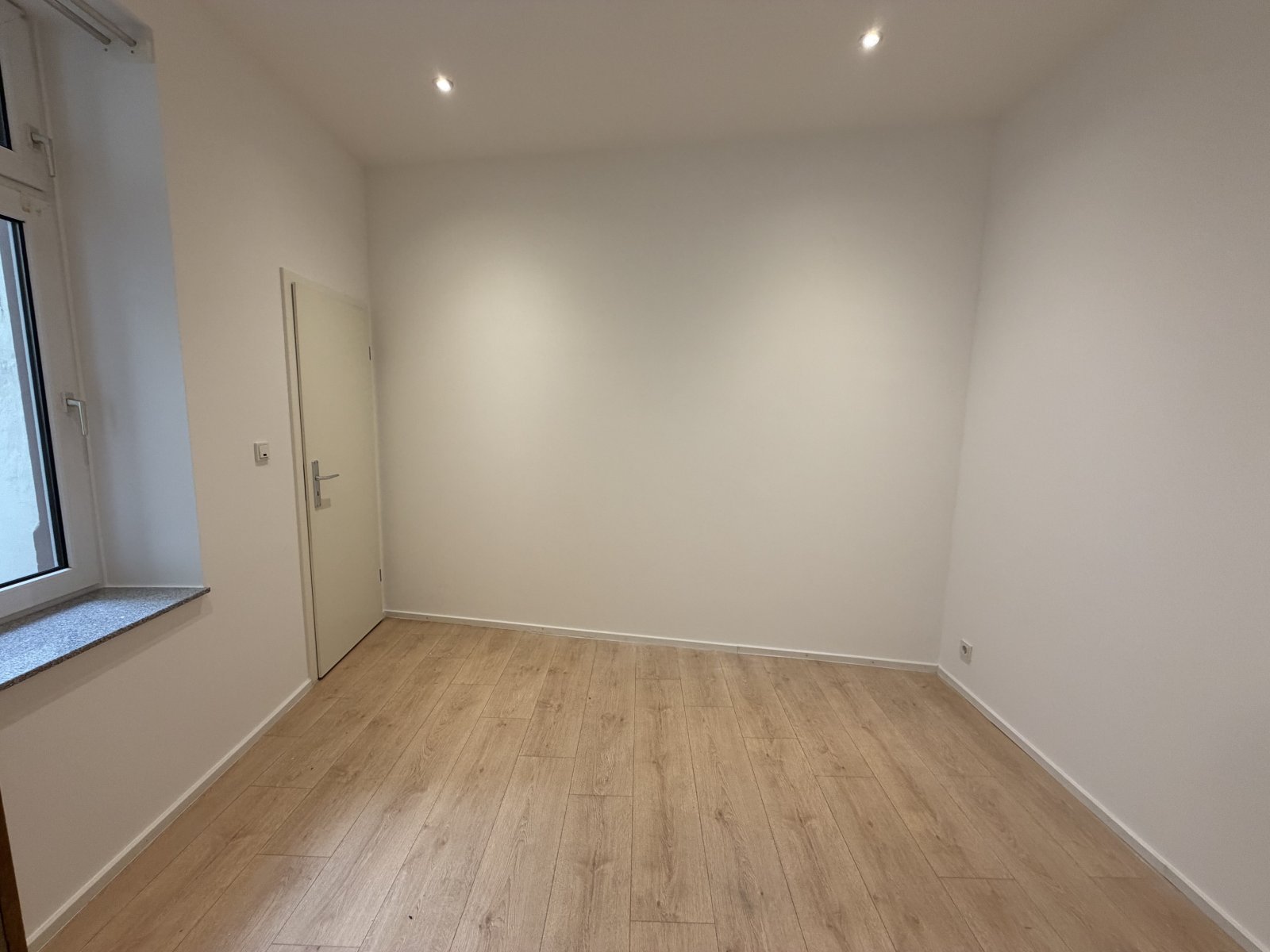 Helles Zimmer mit Parkettboden und moderner LED-Beleuchtung