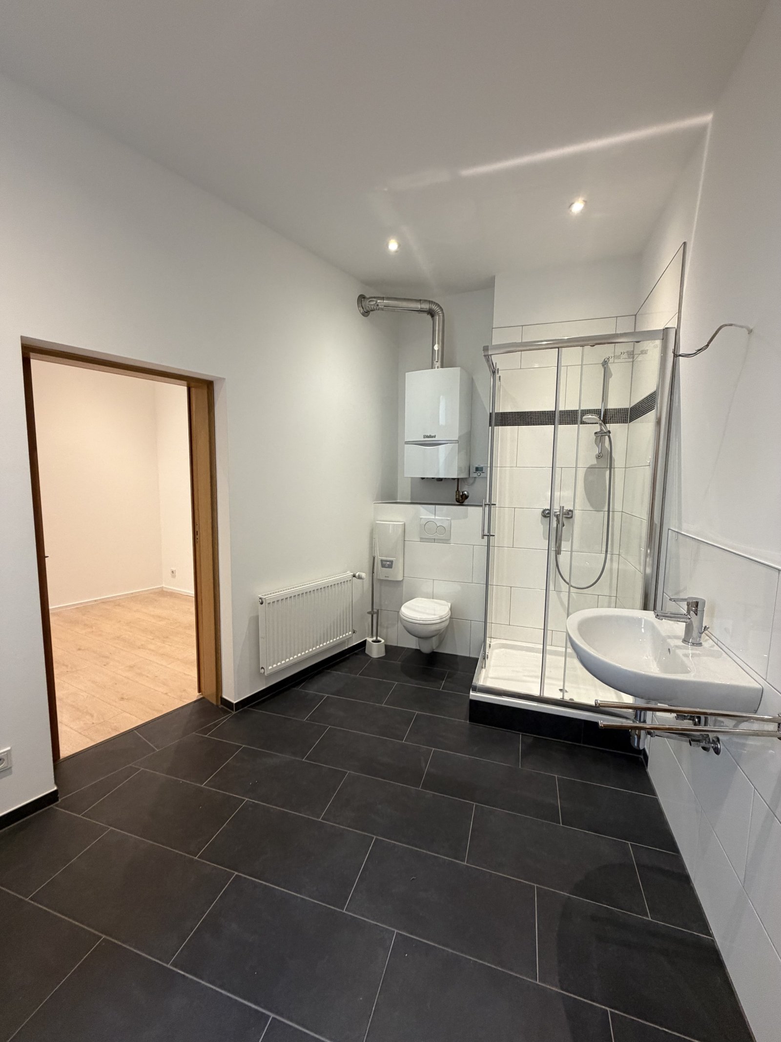 Modernes Badezimmer mit bodenebener Dusche und Gästebereich
